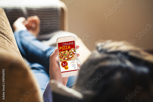 Woman holding a mobile phone with pizza shop website in the screen.