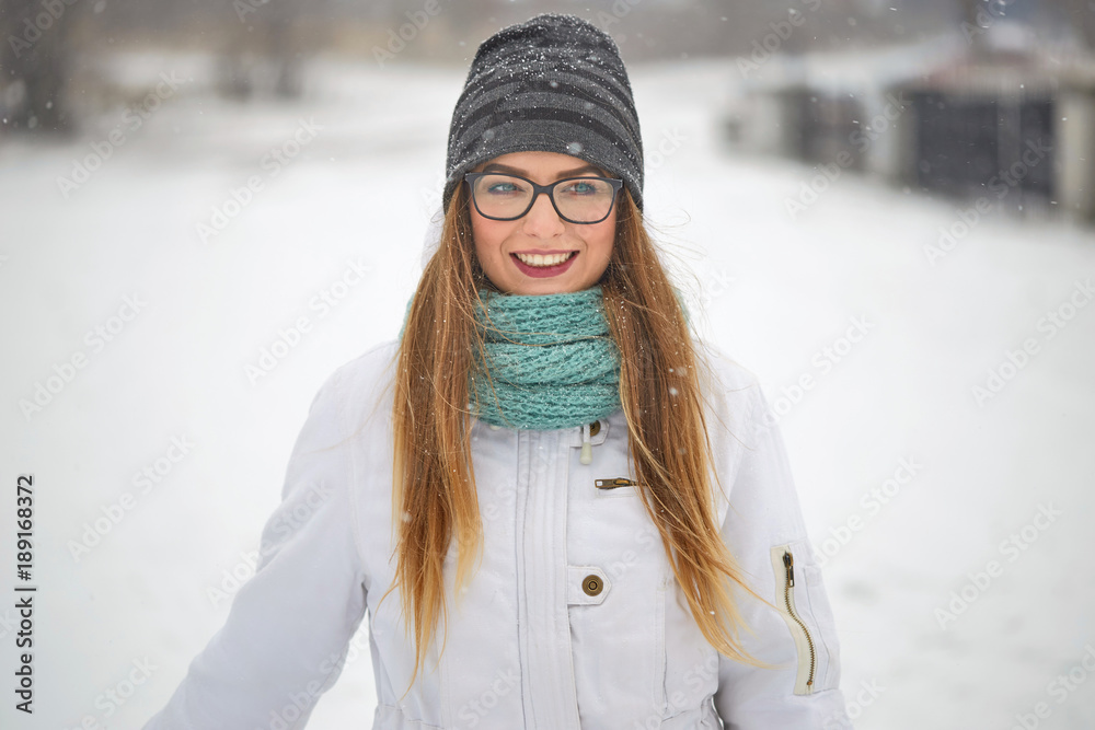 Obraz premium portrait of a cheerful girl with glasses in a snowfall in winter.