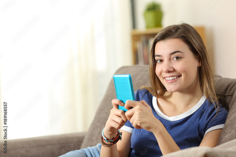 Happy teen holds a smart phone looking at you Happy teen holds a smart phone looking at you