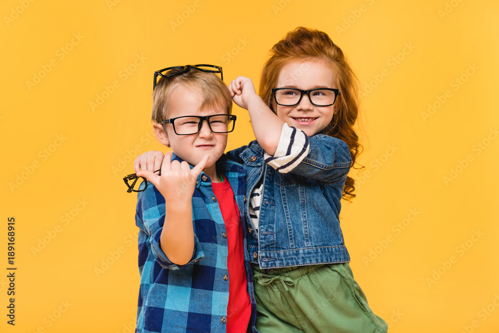 Φωτογραφία portrait of smiling kids in eyeglasses isolated on yellow