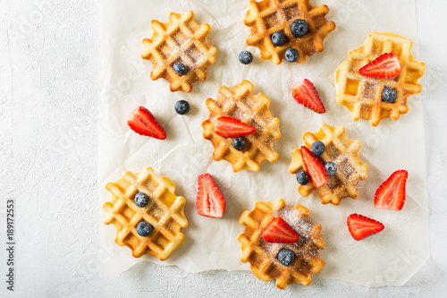 Waffles with stawberries and blueberries border on paper, grey background