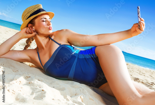 healthy woman on beach taking selfie with smartphone