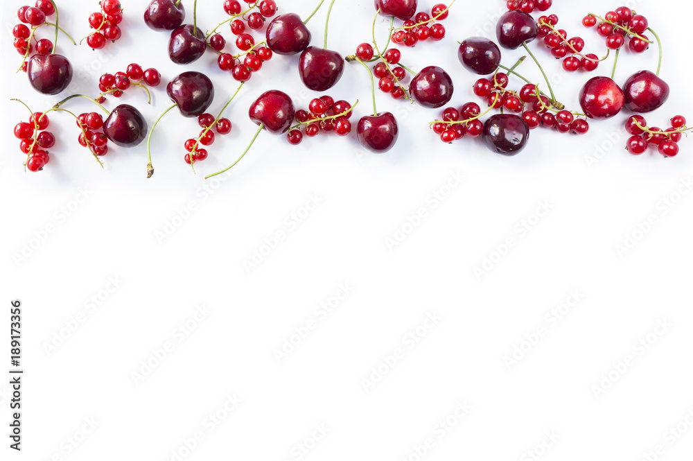 Red food at border of image with copy space for text. Ripe cherries and red currants on a white background. Red berries and fruits. Various fresh summer berries on white background. Top view. Red food at border of image with copy space for text. Ripe cherries and red currants on a white background. Red berries and fruits. Various fresh summer berries on white background. Top view.
