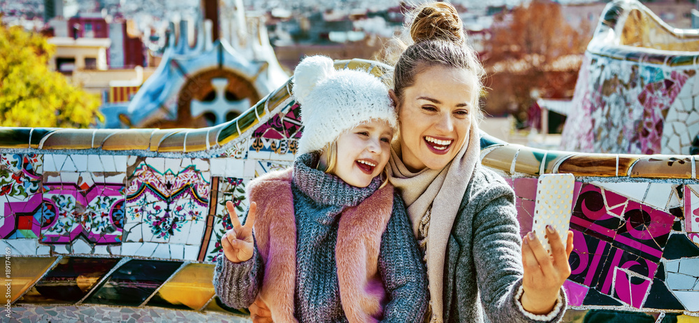 Fototapeta premium smiling mother and daughter tourists taking selfie in Barcelona