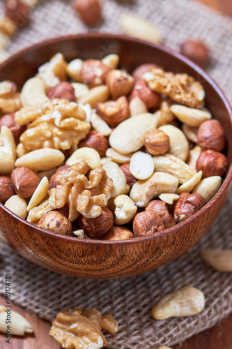 Mixed nuts including hazelnuts, walnuts, blanched almonds and cashews in wooden bowl