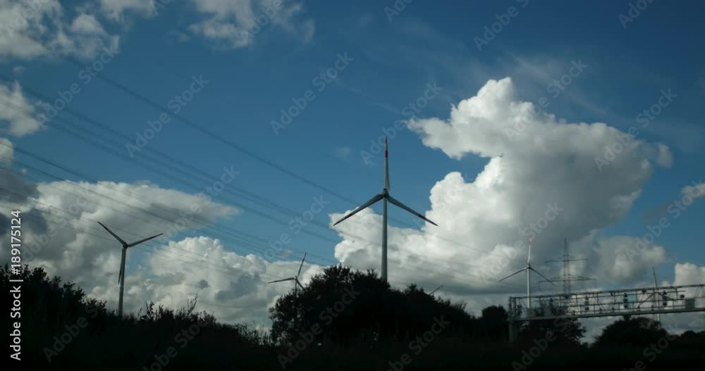 View out of car window passing by windmill farm with wind turbines. Sustainable green energy industry concept. View out of car window passing by windmill farm with wind turbines. Sustainable green energy industry concept.