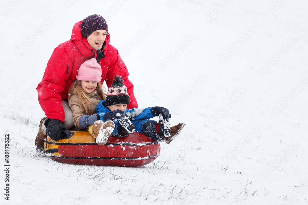 Picture of happy father, daughter and son on tubing in winter park Picture of happy father, daughter and son on tubing in winter park