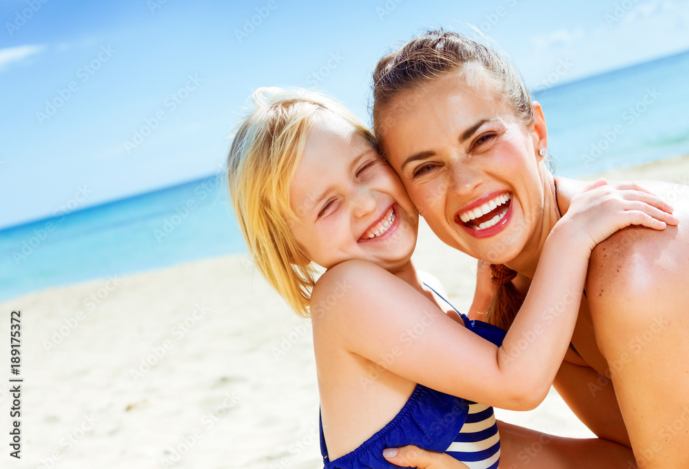 smiling healthy mother and daughter on seashore embracing smiling healthy mother and daughter on seashore embracing