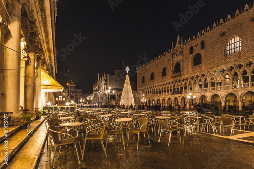 VENICE  ITALY - JANUARY 02 2018  night view of chairs and tables of a bar in Piazza San Marco with the Christmas tree in the background