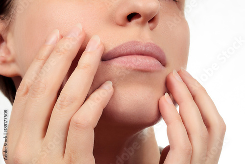 Healthy lips closeup without makeup. Hands show beautiful closed mouth without lipstick. Nails without nail-varnish polish. Beauty. Face without cosmetics on white background.
