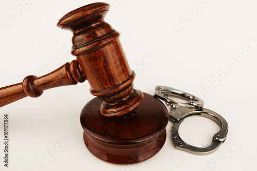 Justice or legal law concept with judge hammer and handcuffs on white background photo