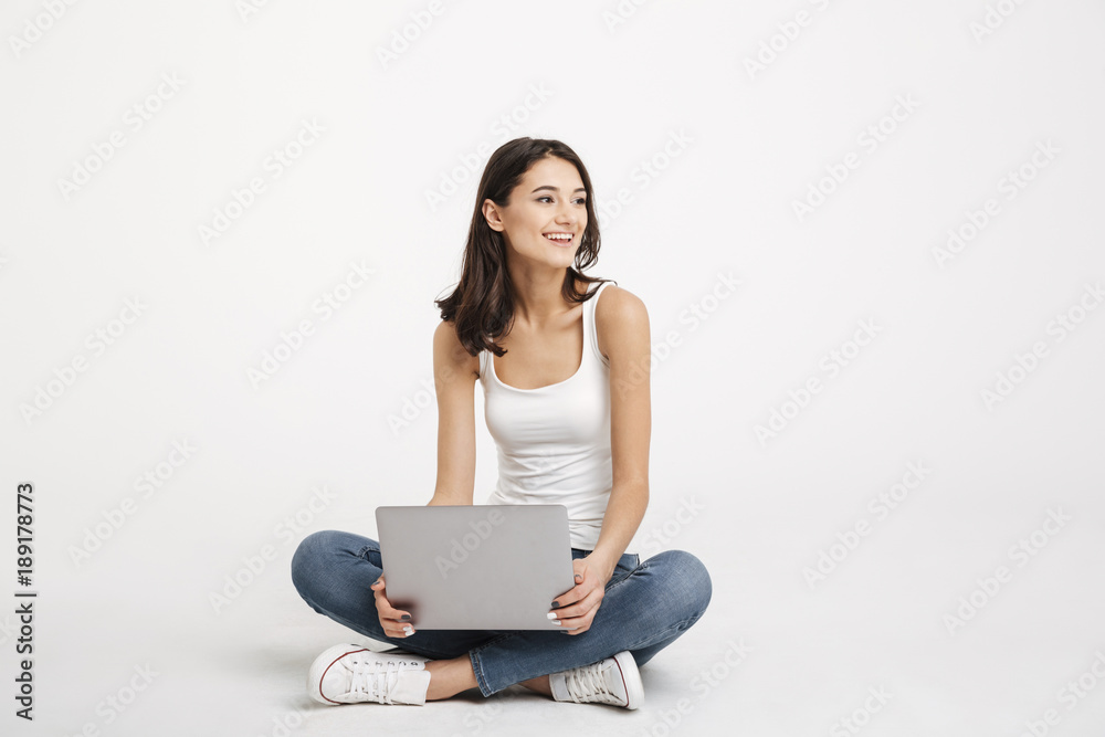Portrait of a cheery girl dressed in tank-top holding laptop Portrait of a cheery girl dressed in tank-top holding laptop