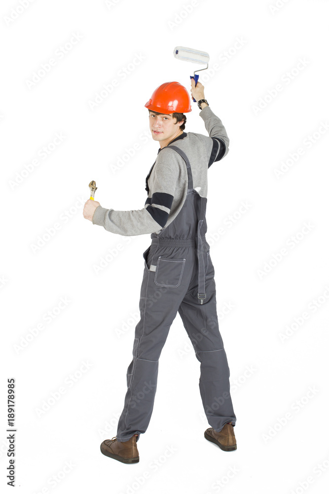 A young man in working grey clothes and orange hard helmet painting the walls in the room. A young man in working grey clothes and orange hard helmet painting the walls in the room.