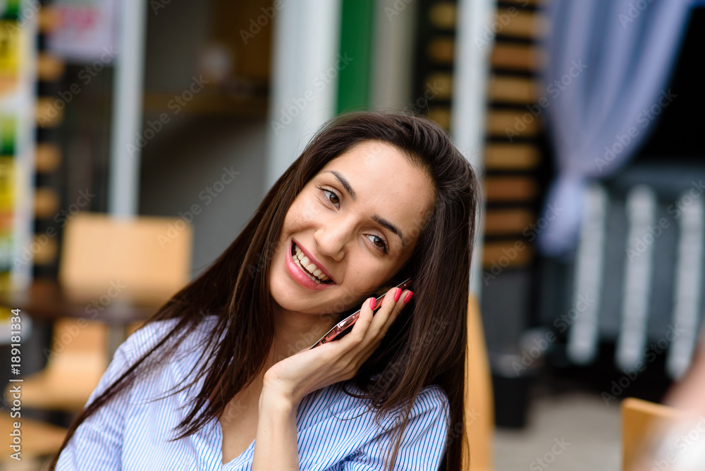 Beautiful woman communicates on the phone in the street.