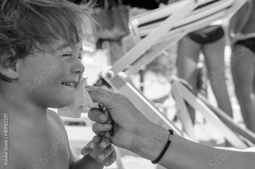 Mother's hand cleaning child face from ice cream