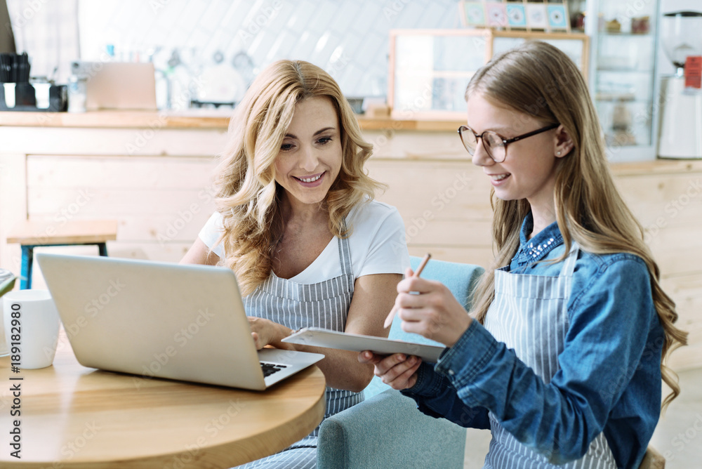 Make notes. Beautiful girl sitting in semi position and looking at her notes while sitting near her mom Make notes. Beautiful girl sitting in semi position and looking at her notes while sitting near her mom