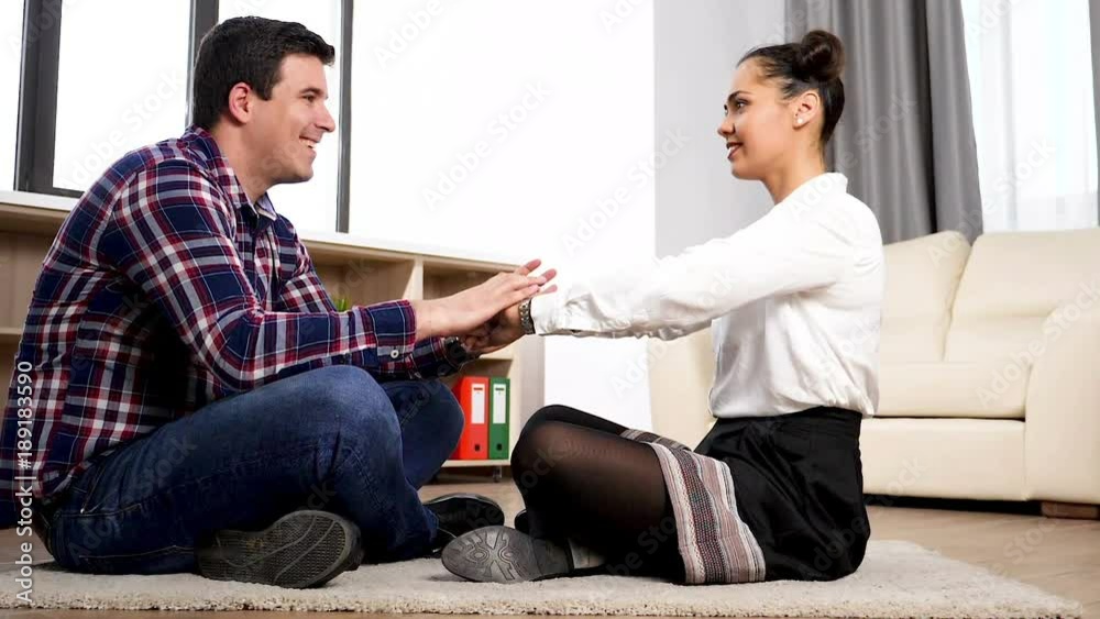 Couple on the floor in their living room and papper heart falling arround them Couple on the floor in their living room and papper heart falling arround them