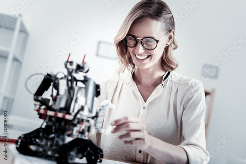 Playful mood. Attractive female person keeping smile on her face and bowing head while playing with toy