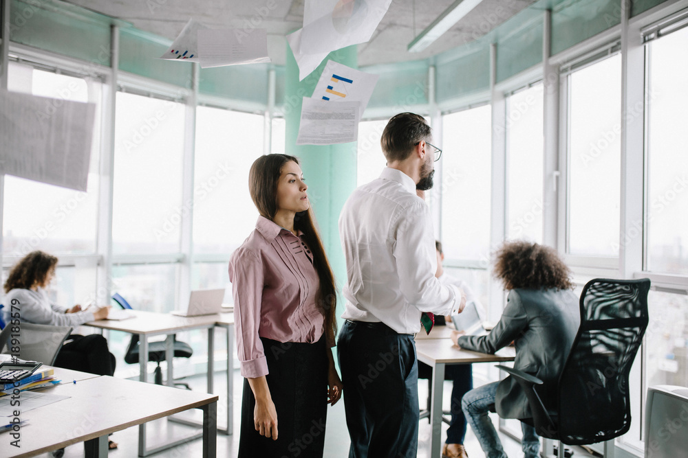 Man and woman standing together under flying documents. Angry because of mistakes. Man and woman standing together under flying documents. Angry because of mistakes.