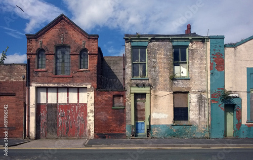derelict houses and abandoned commercial property on a residential street with boarded up windows and decaying crumbling walls