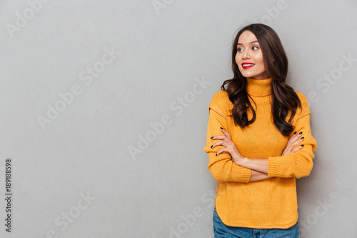 Smiling woman in sweater with crossed arms looking away