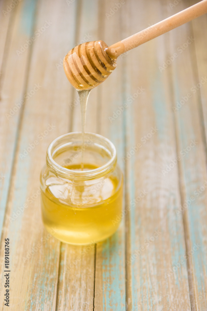 Honey pours with wooden sticks in a jar Honey pours with wooden sticks in a jar