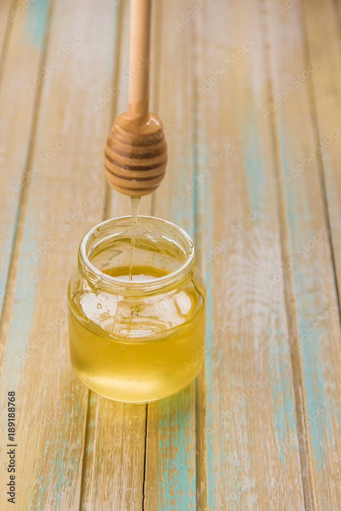 Honey pours with wooden sticks in a jar Honey pours with wooden sticks in a jar