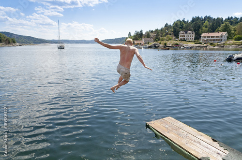 Man jumping off springboard into ocean in the summer