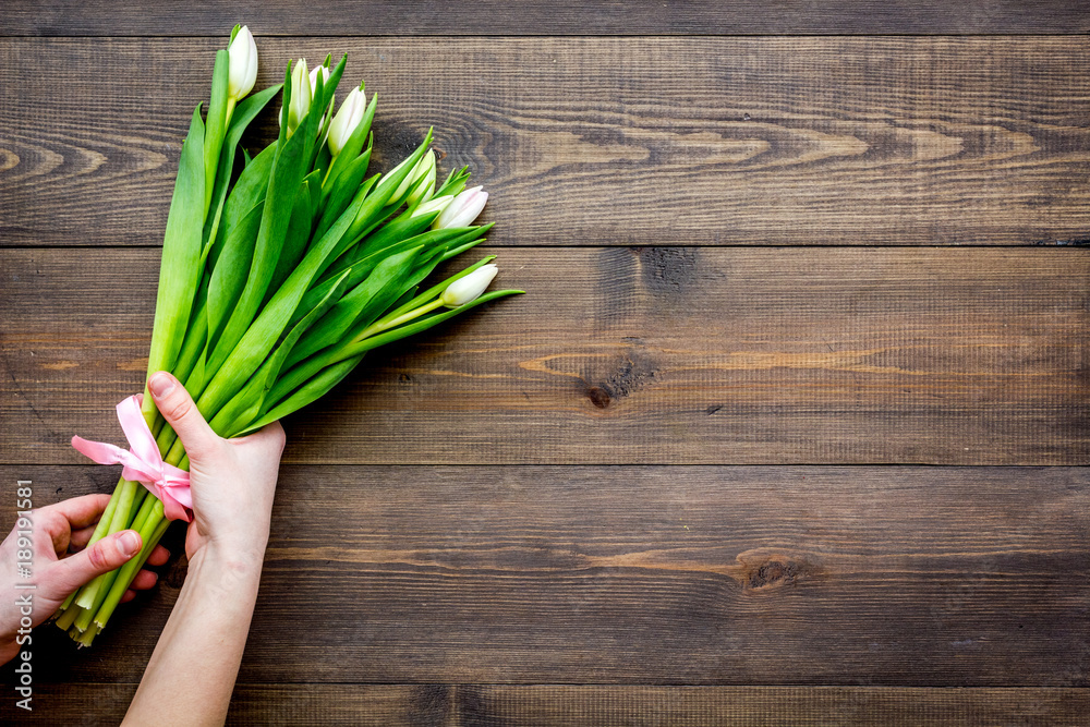 First spring flowers. Bouquet of pale pink tulips on dark wooden background top view copy space First spring flowers. Bouquet of pale pink tulips on dark wooden background top view copy space
