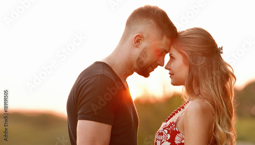 Evening sun illuminates young couple hugging on field