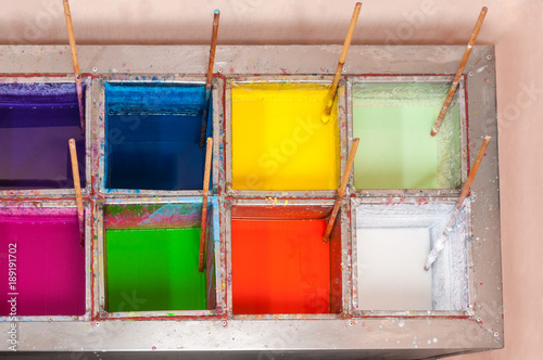 Baths with dyes and bamboo sticks for painting decorative carved candles