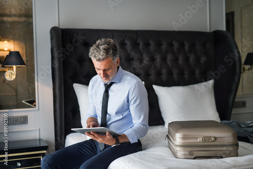 Mature businessman with tablet in a hotel room. photo