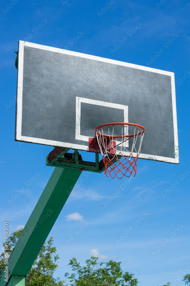 Basketball backboard with blue sky.
