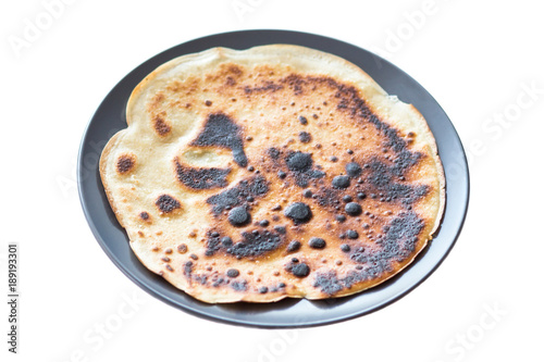 Burnt pancake presented on a plate, isolated