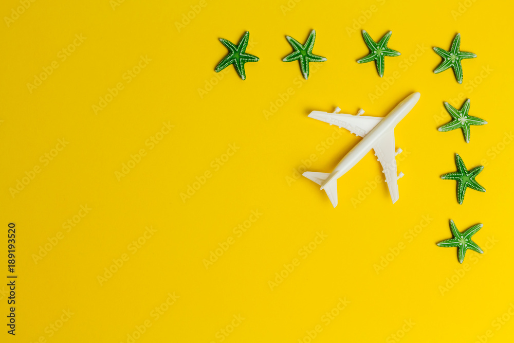 white airplane model and green starfishes in the corner of yellow background white airplane model and green starfishes in the corner of yellow background
