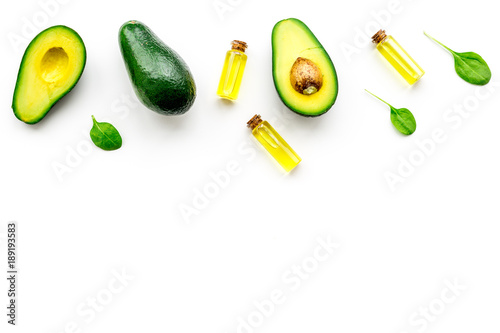 Natural products for skin care. Avocado oil in bottles near sliced avocado on white background top view copy space
