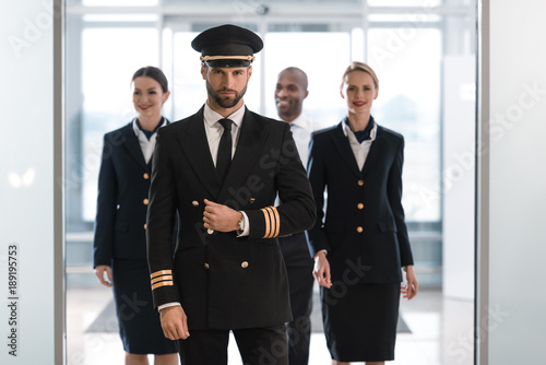 handsome pilot at airport with his team looking at camera