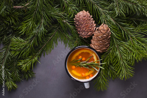 citrus spicy tea, branch branches and cedar cones on a dark background - winter background, warming drink for heat and disease prevention