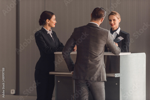 Bild auf Leinwand rear view of young businessman standing at airport check in counter