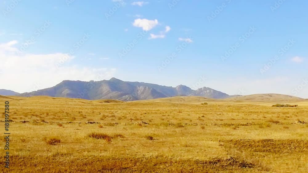 View from window moving car on dusty rural road with desert fields and hills