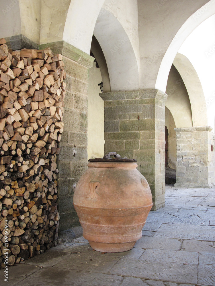 Otre di terracotta e catasta di legna con arcata medievale Otre di terracotta e catasta di legna con arcata medievale