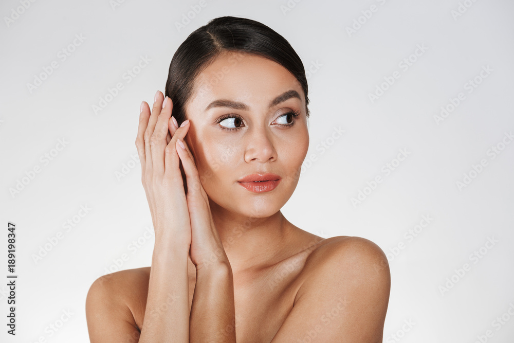 Close up portrait of beautiful woman with natural makeup looking aside and holding hands close to her healthy face, isolated over white background Close up portrait of beautiful woman with natural makeup looking aside and holding hands close to her healthy face, isolated over white background
