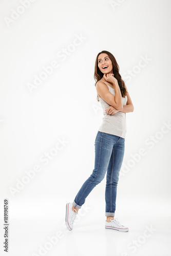 Full length image of Happy brunette woman posing and looking back