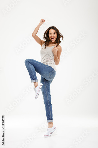 Full length image of Happy brunette woman rejoices