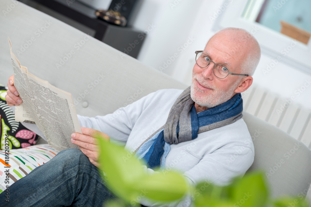 handsome mature man reading newpaper on sofa