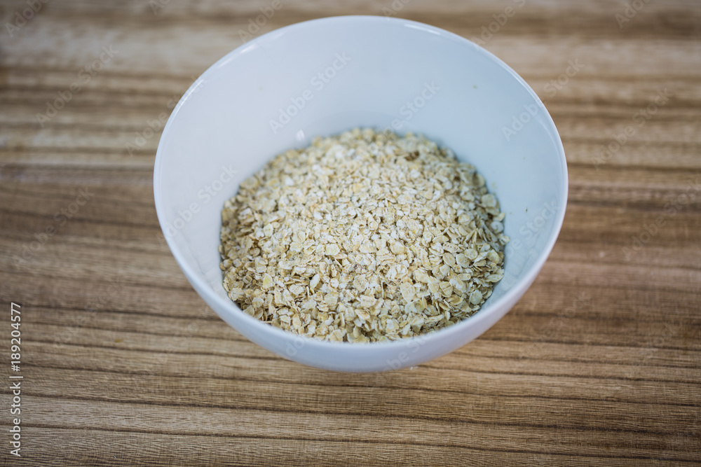 Oatmeal in a white cup, wooden background Oatmeal in a white cup, wooden background