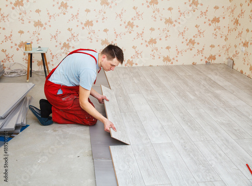handyman laying down laminate flooring boards © Radnatt