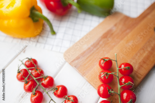 Diet, Healthy Food Cooking, Vegetarian Concept. Set of Pizza or Pasta indredients: fresh cherry tomatoes on a cutting board, paprika peppers, white wood and plaid napkin as a background
