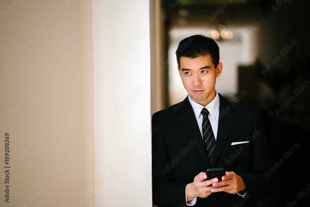 Portrait of young handsome man standing in a well lit corridor. He is wearing formal business attire and looks concerned, worried and serious. Portrait of young handsome man standing in a well lit corridor. He is wearing formal business attire and looks concerned, worried and serious.