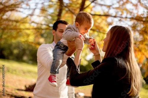 Happy young parents with baby boy in autumn park